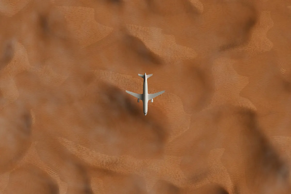 Business jet flying low over rippled desert sand