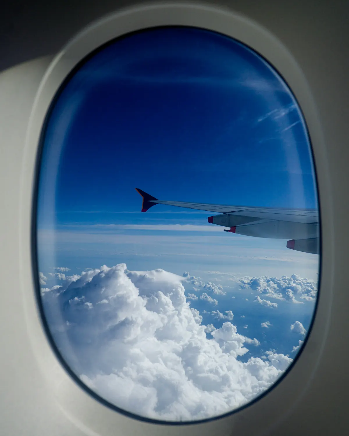 View of a wing and blue sky through an aircraft window